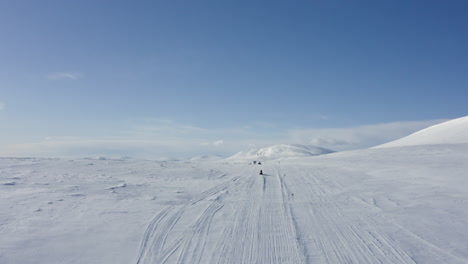 Aerial-wide-shot-of-people-on-snowmobiles-driving-on-snow-tracks-in-winter-landscape-in-Sweden