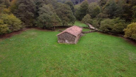 Drone-view-of-a-barn-house-in-the-middle-of-a-forest,-in-the-mountains,-Pyrenees,-Spain,-autumn-landscapes-scenery