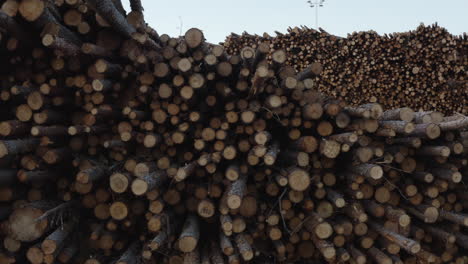4k-Aerial-shot-moving-sideways-of-large-piles-of-timber,-logs-and-wood-at-a-factory-in-Sweden