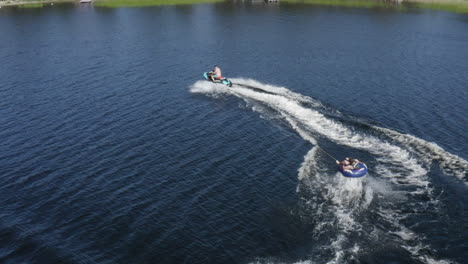 Young-men-diding-a-jet-ski-and-a-ringo-ride-on-a-lake-in-Sweden-on-a-hot-summer-day