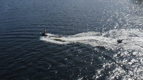 Aerial-view-of-young-men-enjoying-life-while-riding-on-a-ringo-and-jet-ski-in-super-slow-motion