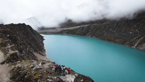 Drone-shot-of-friends-in-a-cloudy-turquoise-lake-in-the-highlands-and-mountains-of-Huaraz-Peru