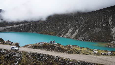 Circling-drone-shot-of-a-group-of-friends-in-a-blue-lagoon-in-the-mountains-of-Huaraz