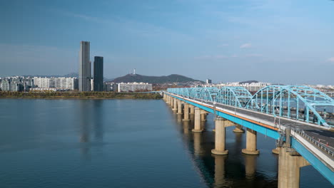 Aerial-Time-Lapse-of-Cars-Traffic-Driving-on-Dongjak-Bridge-Crossing-Over-Han-River,-distant-view-of-N-Seoul-Tower-in-Skyline,-South-Korea