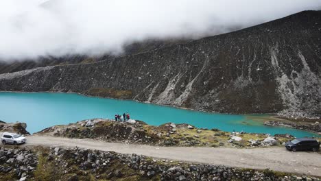 Drone-shot-of-friends-next-to-a-turquoise-lake-in-the-cloudy-mountains-of-Yungay-Peru