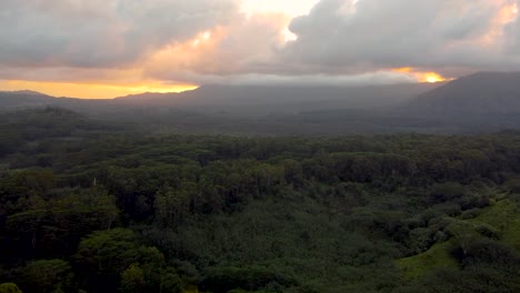 Cinematic-aerial-flyover-revealing-lush-green-rainforest,-rivers-and-green-mountains-with-sunset-clouds