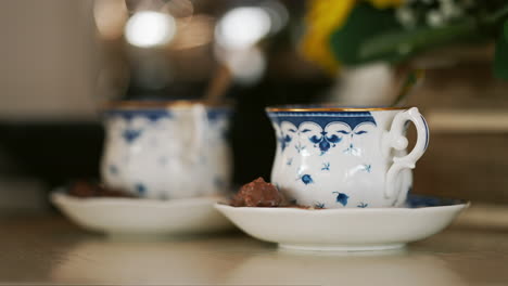Closeup-Shot-of-Two-Steaming-Cups-of-Tea-with-Chocolate-in-the-Morning