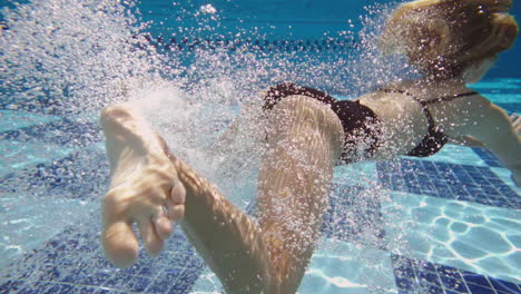 blonde-hair-girl-jumping-underwater,-shooting-from-pool