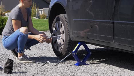 Young-female-repairing-damaged-car-tyre-roadside-vehicle-breakdown