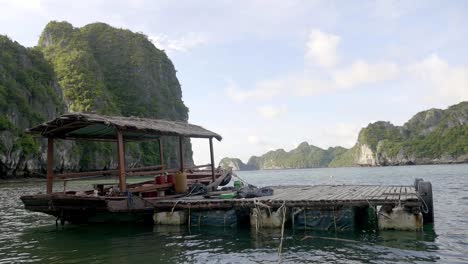 A-Traditional-Vietnamese-Roofed-Fishing-Boat-Docked-On-A-Wooden-Platform-On-Empty-Plastic-Containers---Wide-Shot