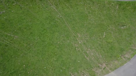 drone-aerial-view-slowly-rotating-around-a-single-cyclist-cycling-on-a-mountain-road-surrounded-by-grass