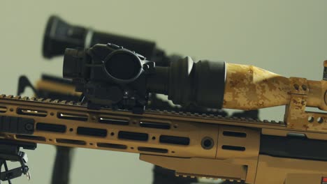 Black-scope-on-top-of-a-beige,-army-tinted-rifle