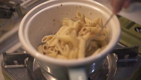 Cooking-spaghetti-aglio-e-olio-penne-pasta-in-white-bowl-over-stove-spoon,-closeup