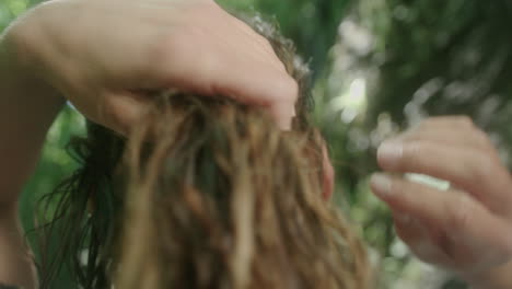 Female-running-hands-through-dark-wet-hair-in-forest-shot-in-slowmotion