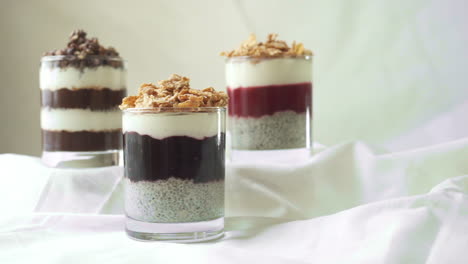Selection-of-layered-chia-puddings-with-hand-taking-one-and-putting-it-back