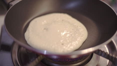 Fluffy-pancake-cooking-on-heat-stove-pan-closeup