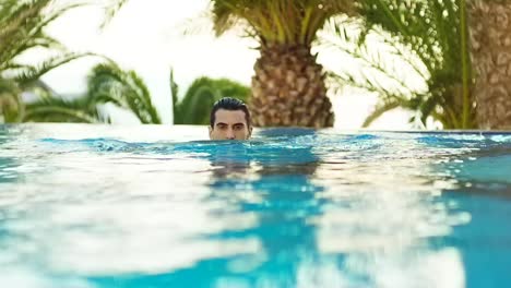 The-model-swims-in-the-pool-surrounded-by-palm-trees