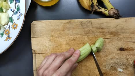 Food-preparation-cutting-cucumber-on-a-wood-surface-for-salad