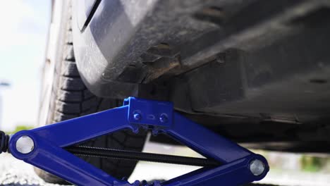 Closeup-hydraulic-car-jack-adjustable-scissor-lift-under-vehicle-for-inspection
