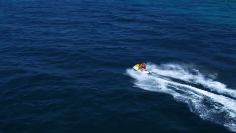 Aerial-view-of-the-couple-riding-the-jetski-in-the-sea-by-drone