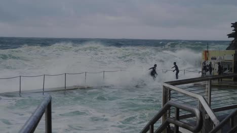 Huge-Waves-Crashing-On-The-Pool-In-Bronte-Beach-With-People-Taking-The-Risk---Dangerous-Storm-In-Sydney,-NSW,-Australia---wide-shot