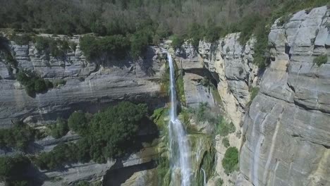 Fast-aerial-back-reveal-of-a-breathtaking-waterfall-on-a-rocky-steep-cliff
