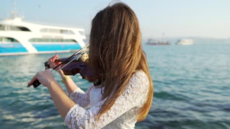 Back-shot-of-the-girl-playing-the-violin-by-the-sea
