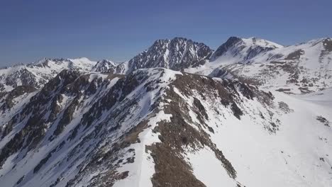 Volando-Sobre-La-Cordillera-Cubierta-De-Nieve,-Destino-De-Esquí-Alpino,-Antena
