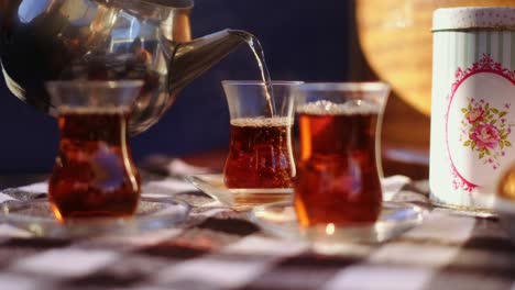 Black-tea-being-poured-into-a-traditional-Turkish-tea-glass-on-checker-table-cloth