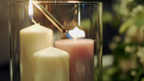 White-candles-inside-a-glass-candle-holder-being-lit