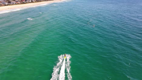 Motorboat-Speeding-Across-The-Bright-Blue-Sea---Water-Adventure-In-Palm-Beach,-Gold-Coast---tilt-up-drone