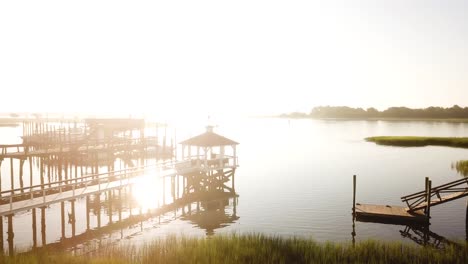 Peaceful-morning-sunrise-drone-right-pan-from-pier,-waterway,-houses,-and-marsh-at-Trails-End-Park-in-Wilmington-North-Carolina