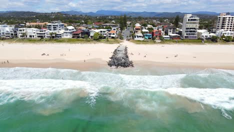 People-On-The-Sand-With-Rock-Groyne---Summer-At-Palm-Beach,-Gold-Coast,-QLD---pullback-drone-shot
