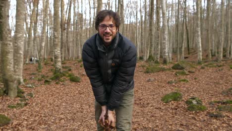 Lächelnder-Mann-Lächelt-Wirft-Trockene-Blätter-In-Richtung-Kamera-Im-Wald