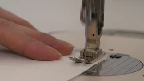 Sewing-Machine-Needle-Moving-Up-and-Down-into-White-Cloth,-Extreme-Closeup