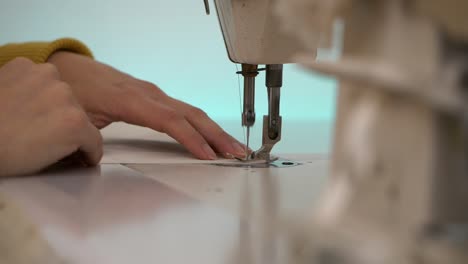 Woman's-hands-guiding-white-fabric-in-sewing-machine,-Slow-Motion-Close-Up