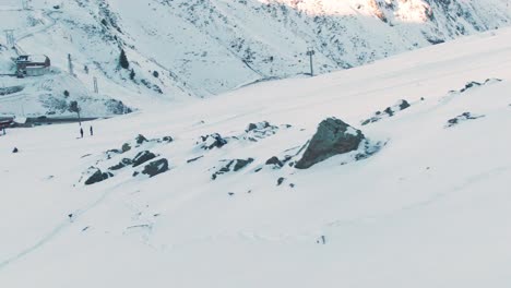 drone-aerial-view-following-a-skier-passing-through-rocks-on-a-snow-piste-in-the-french-alps-Europe