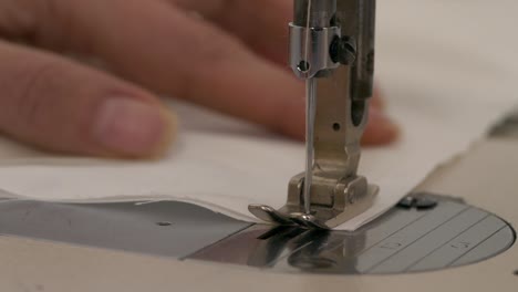 Close-up-of-hand-holding-still-fabric-while-sewing-machine-needle-sews
