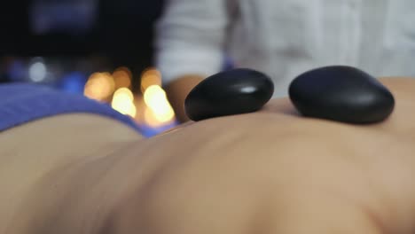 masseuse-puts-hot-therapy-stones-on-woman's-back-in-slow-motion