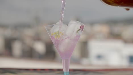 Verter-Una-Bebida-De-Limonada-De-Vodka-Rosa-En-Una-Copa-De-Cóctel-Con-Cubitos-De-Hielo-Florales