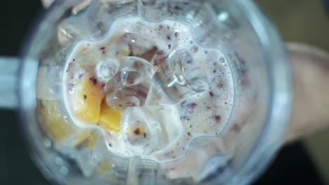 Frozen-blended-in-slow-motion-shot-from-above-using-fruit-strawberries,-orange-and-yoghurt-with-ice