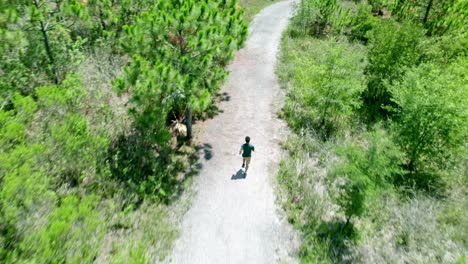 Aerial-video-of-Caucasian-man-running-in-sunny-green-public-park