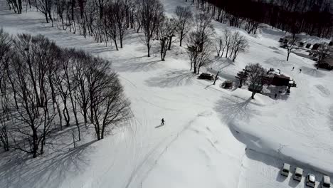 Aerial---drone-shot-of-chairlift-carrying-skiiers-up-snowy-mountain