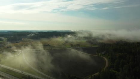 Static-aerial-view-of-morning-fog-floating-over-a-4-lane-highway-with-cars-and-trucks