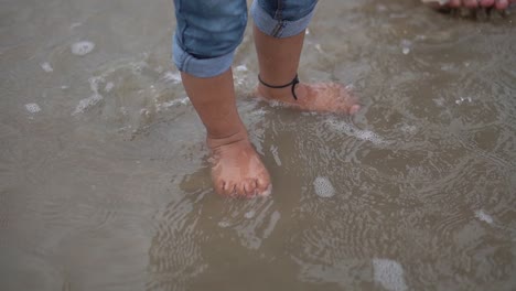 Cute-close-up-shot-legs-of-the-baby-that-makes-first-steps-on-the-sand-beach
