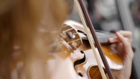 Over-the-shoulder-view-of-a-young-lady-playing-her-violin,-close-up