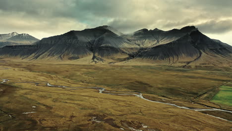 Drone-footage-flying-over-river-valley-towards-a-mountain-range-in-Iceland