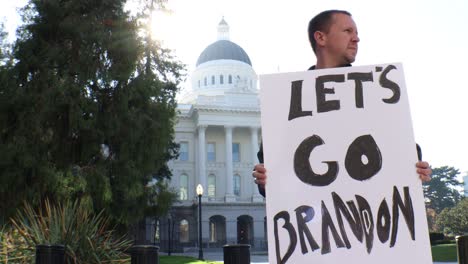Male-Political-Protester-with-Let's-Go-Brandon-Sign-Slider-Dolly-Tracking-Shot