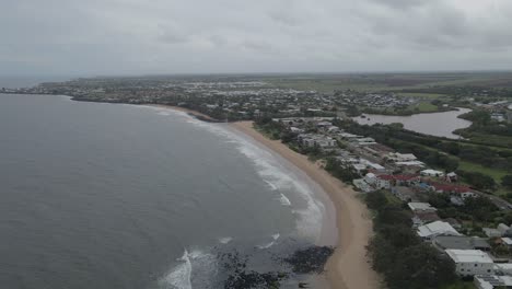 Ocean-To-Beach-Front-Coastal-Town-During-A-Cloudy-Day-In-Bundaberg,-Queensland,-Australia---aerial-drone-shot
