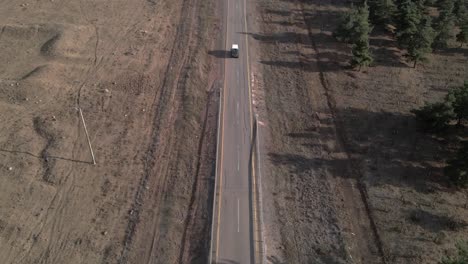 Aerial-view-of-bus-approaching-driving-on-a-road-in-a-dry-landscape-in-Israel,-Golan-Heights